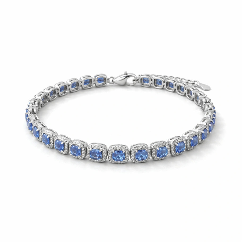 Silver bracelet with blue stones on a beige surface with green leaves