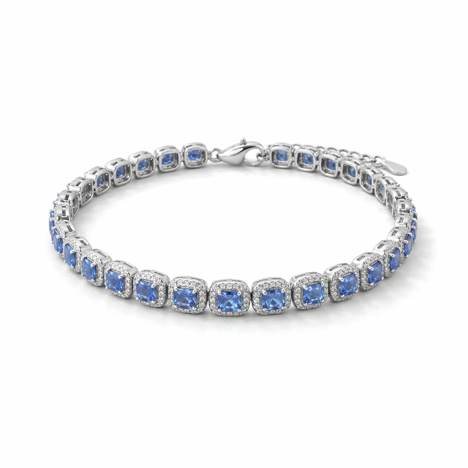 Silver bracelet with blue stones on a beige surface with green leaves