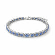 Silver bracelet with blue stones on a beige surface with green leaves