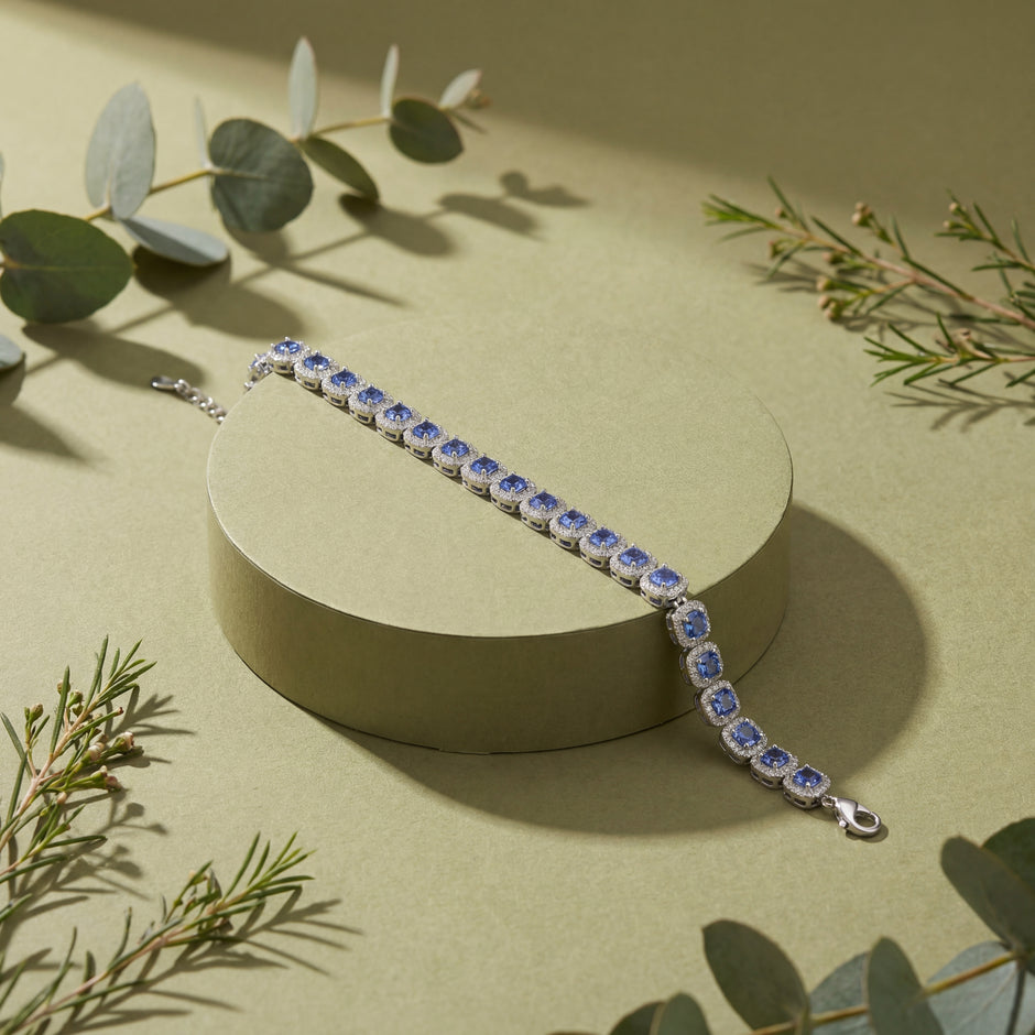 Silver bracelet with blue stones on a beige surface with green leaves