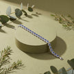 Silver bracelet with blue stones on a beige surface with green leaves