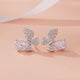 Butterfly-shaped earrings with pink gemstones on a peach background
