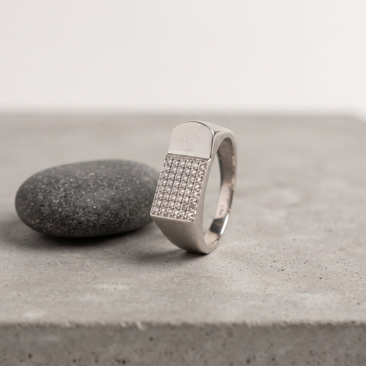 Silver ring with a rectangular pavé-set face and wide polished band.