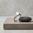 Silver ring with a rectangular pavé-set face and wide polished band.