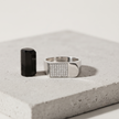 Silver ring with a rectangular pavé-set face and wide polished band.