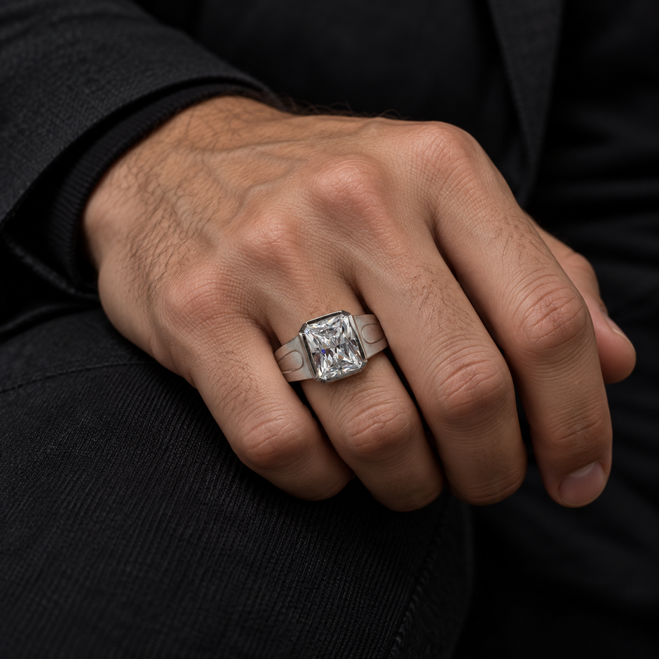 Silver ring with a large rectangular clear stone and engraved geometric band.