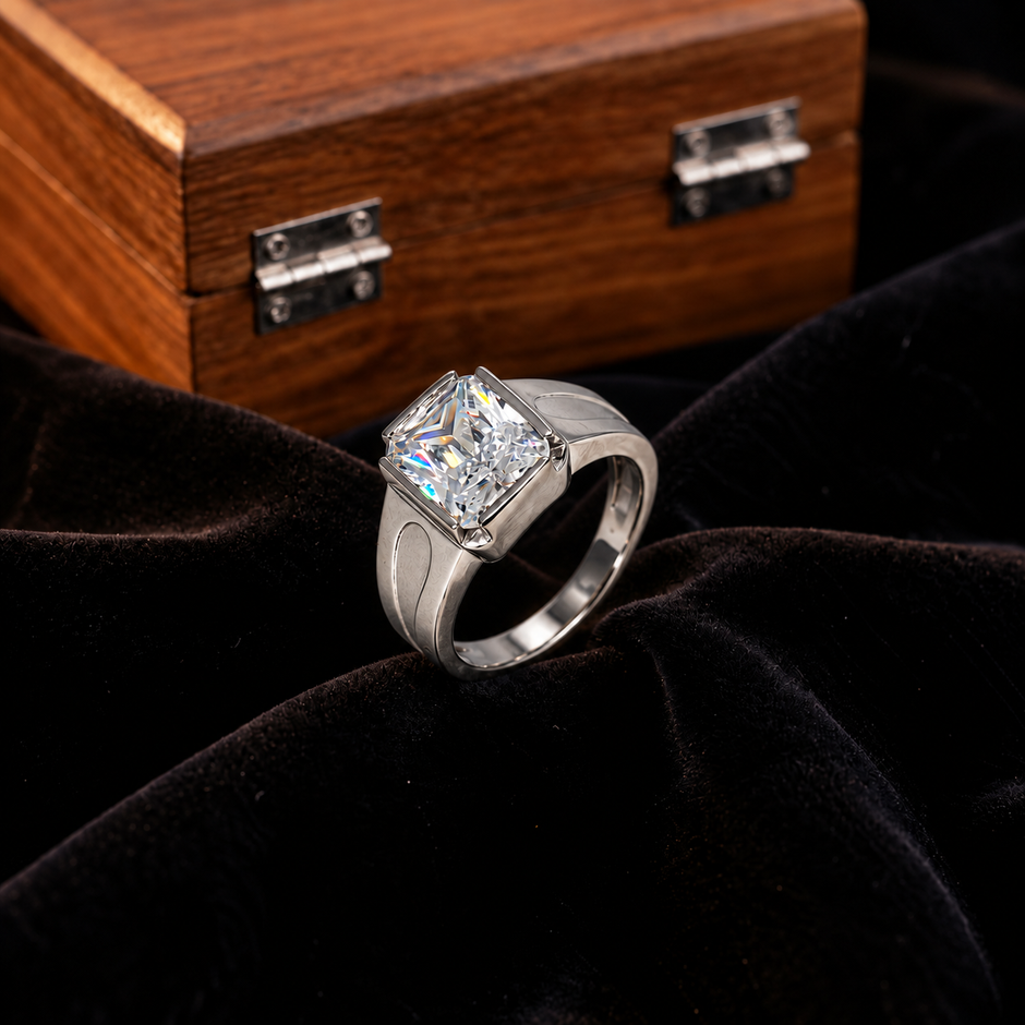 Silver ring with a large rectangular clear stone and engraved geometric band.