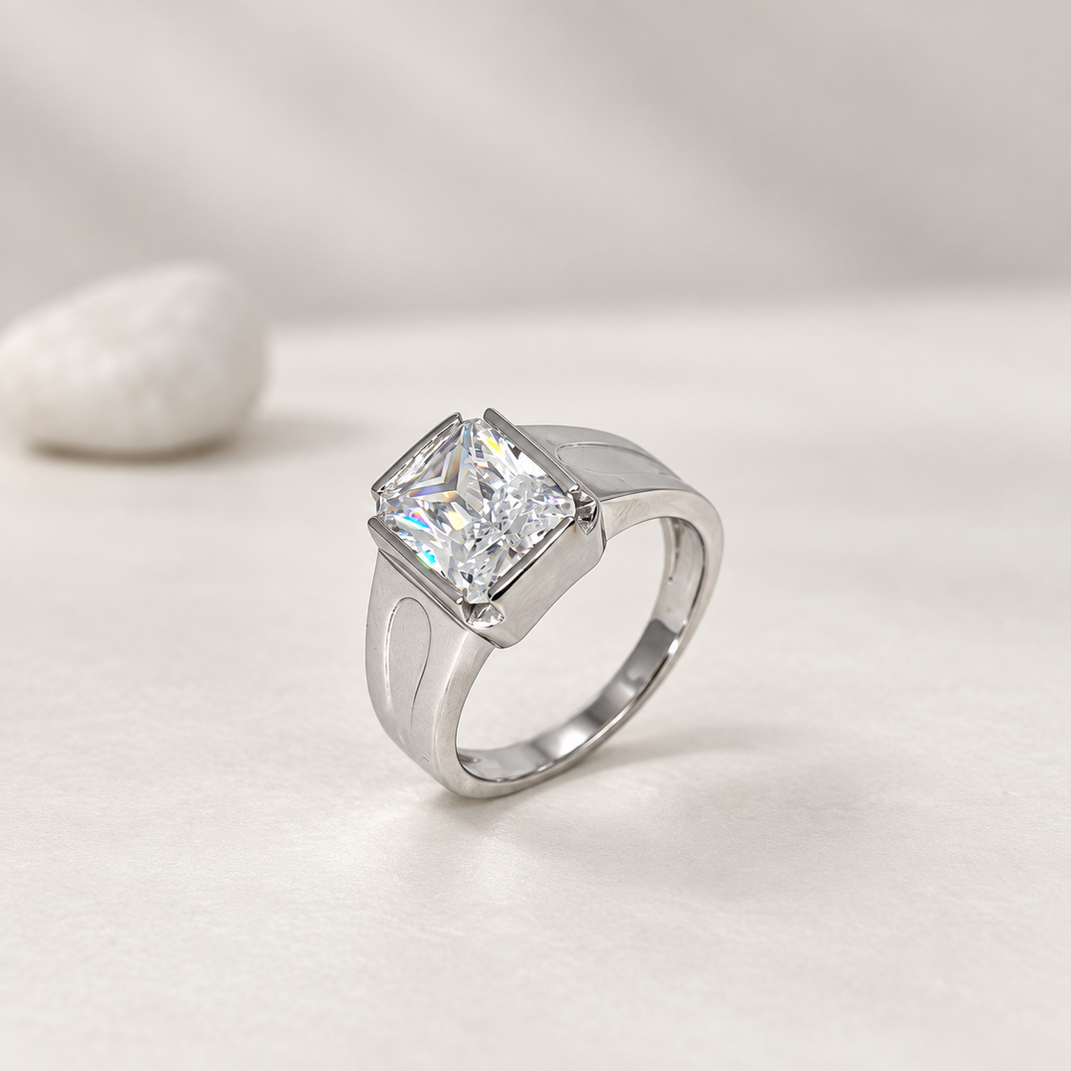 Silver ring with a large rectangular clear stone and engraved geometric band.