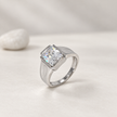 Silver ring with a large rectangular clear stone and engraved geometric band.