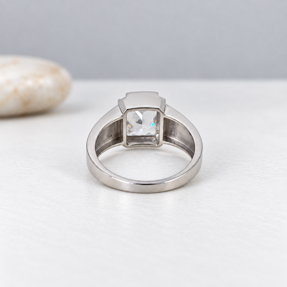 Silver ring with a large rectangular clear stone and engraved geometric band.