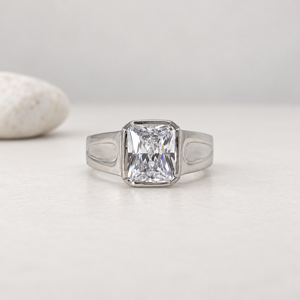 Silver ring with a large rectangular clear stone and engraved geometric band.