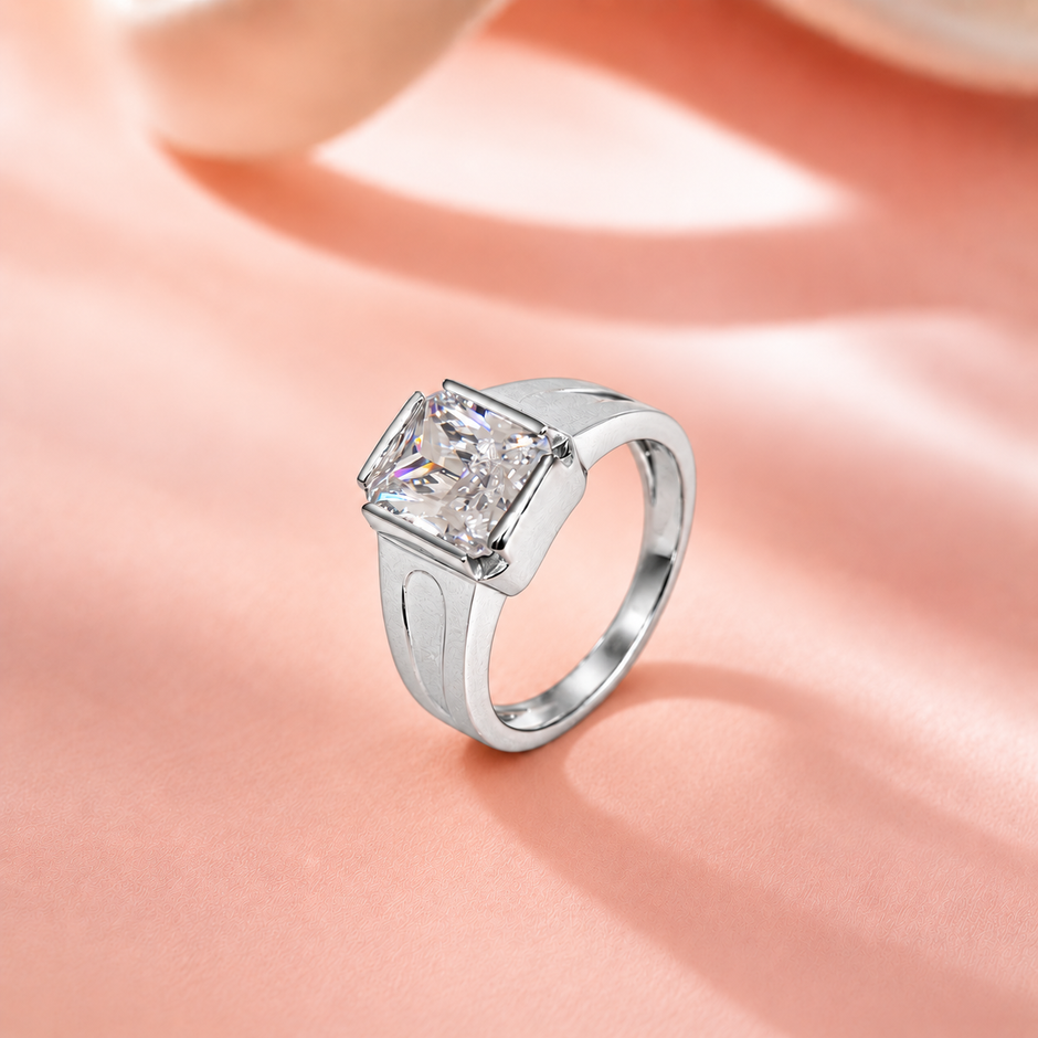 Silver ring with a large rectangular clear stone and engraved geometric band.