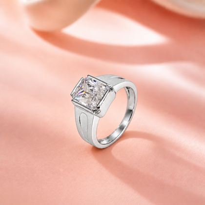 Silver ring with a large rectangular clear stone and engraved geometric band.