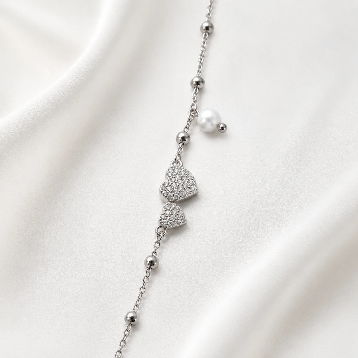 925 Sterling Silver Bracelet with Double CZ Heart Charms, Pearl Drop, and Beaded Chain on White Background