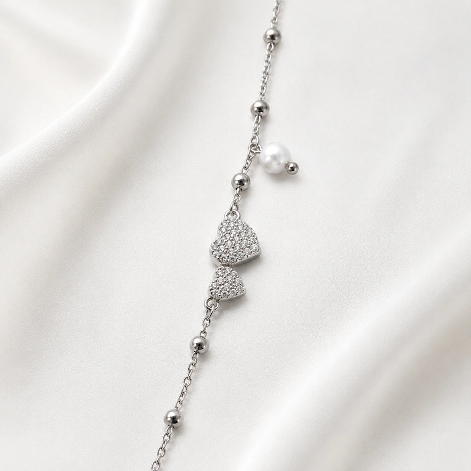 925 Sterling Silver Bracelet with Double CZ Heart Charms, Pearl Drop, and Beaded Chain on White Background