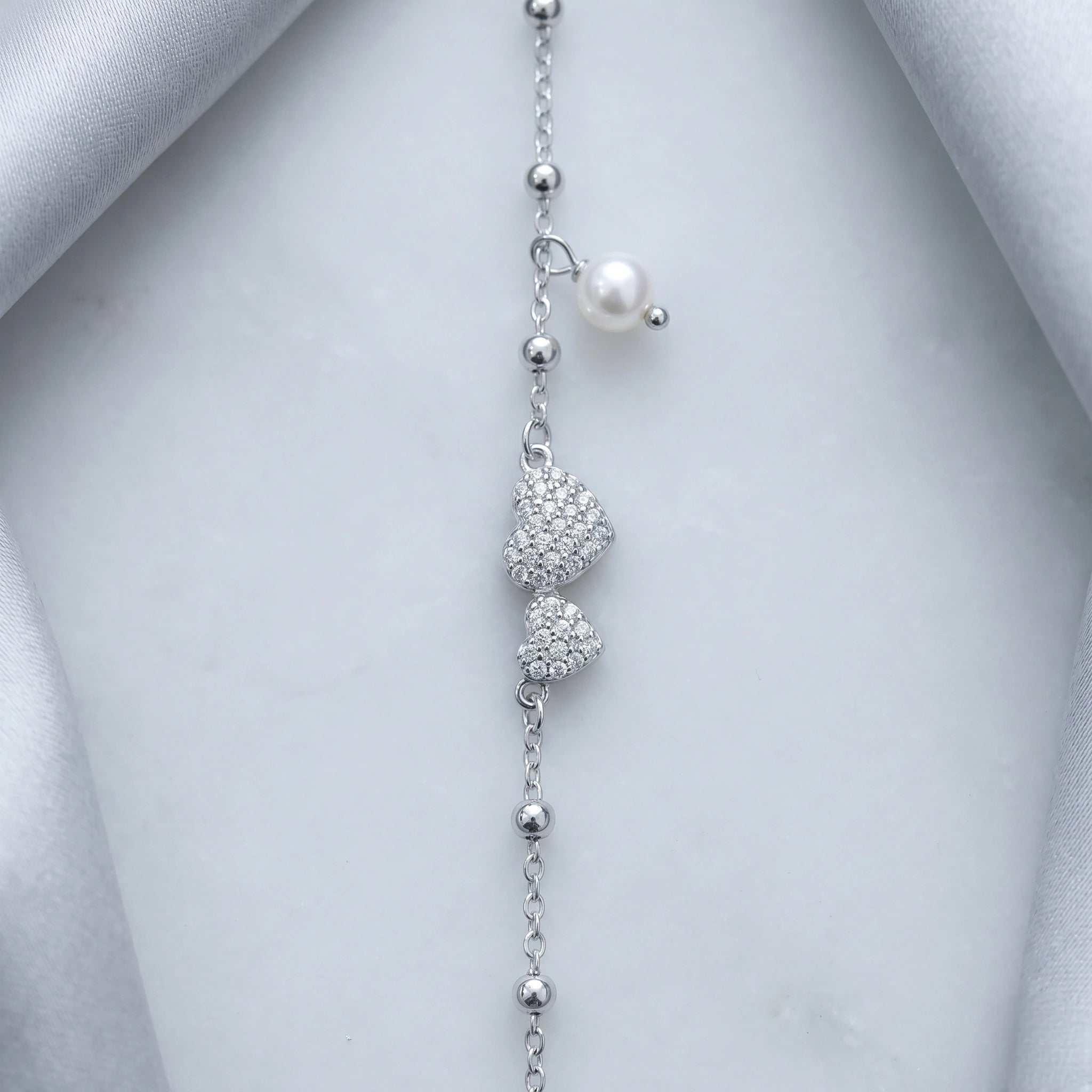 925 Sterling Silver Bracelet with Double CZ Heart Charms, Pearl Drop, and Beaded Chain on White Background