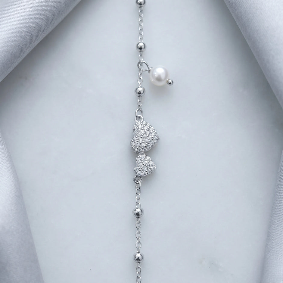 925 Sterling Silver Bracelet with Double CZ Heart Charms, Pearl Drop, and Beaded Chain on White Background