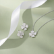 Silver flower necklace and earrings on a light green background with a white ribbon.