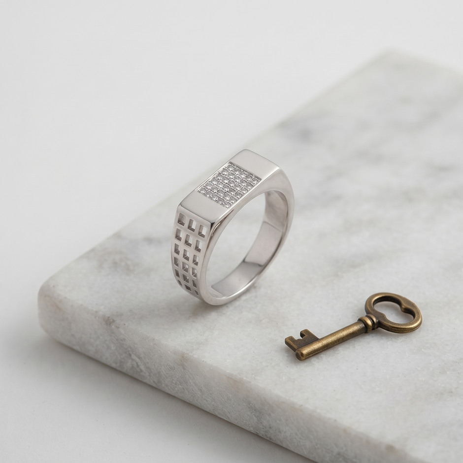 Silver ring with a rectangular stone-studded face and square lattice cutout band.