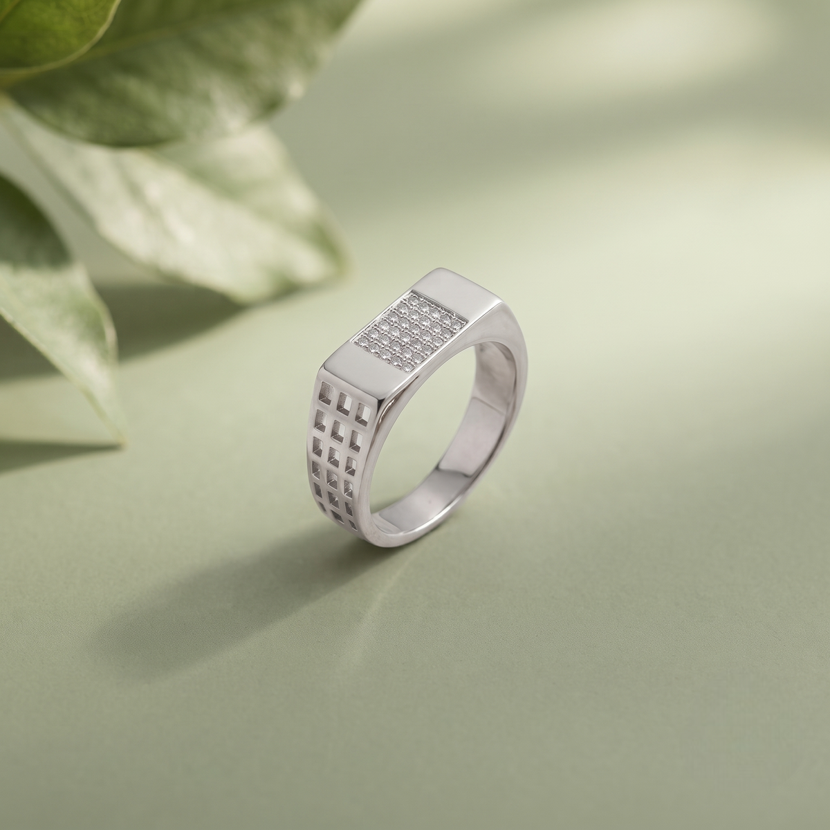 Silver ring with a rectangular stone-studded face and square lattice cutout band.