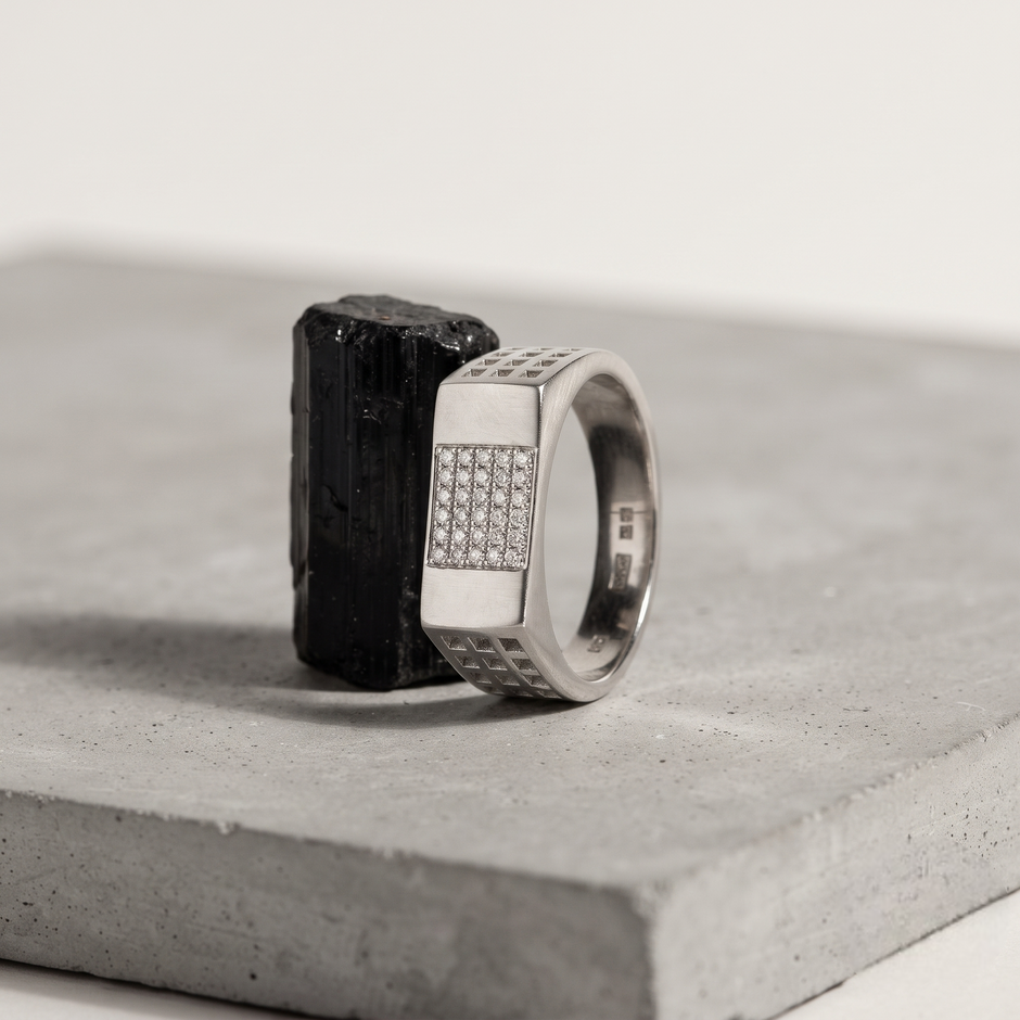Silver ring with a rectangular stone-studded face and square lattice cutout band.