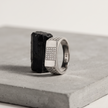 Silver ring with a rectangular stone-studded face and square lattice cutout band.