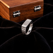 Silver ring with a rectangular stone-studded face and square lattice cutout band.