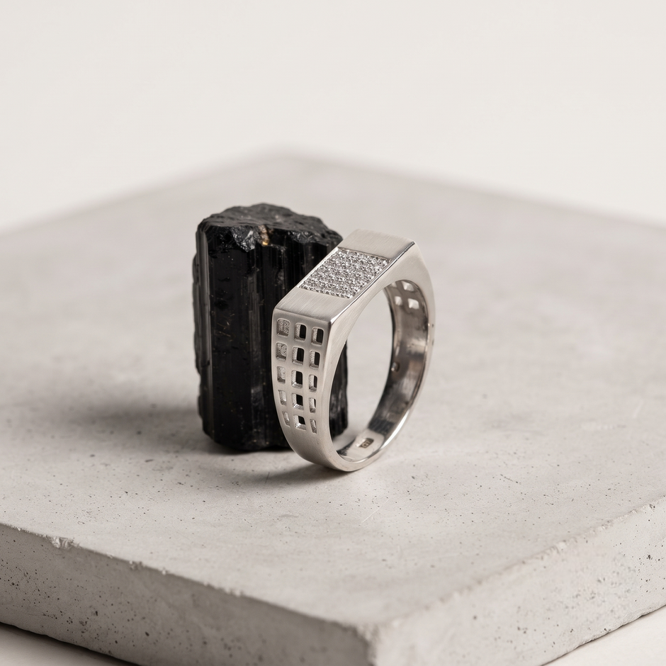 Silver ring with a rectangular stone-studded face and square lattice cutout band.