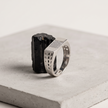 Silver ring with a rectangular stone-studded face and square lattice cutout band.