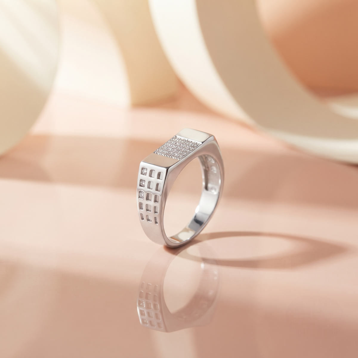 Silver ring with a rectangular stone-studded face and square lattice cutout band.