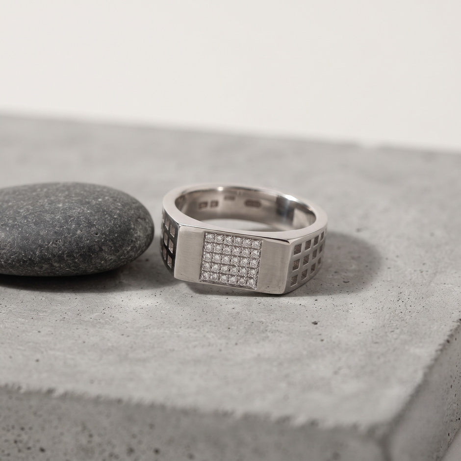 Silver ring with a rectangular stone-studded face and square lattice cutout band.