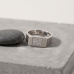 Silver ring with a rectangular stone-studded face and square lattice cutout band.