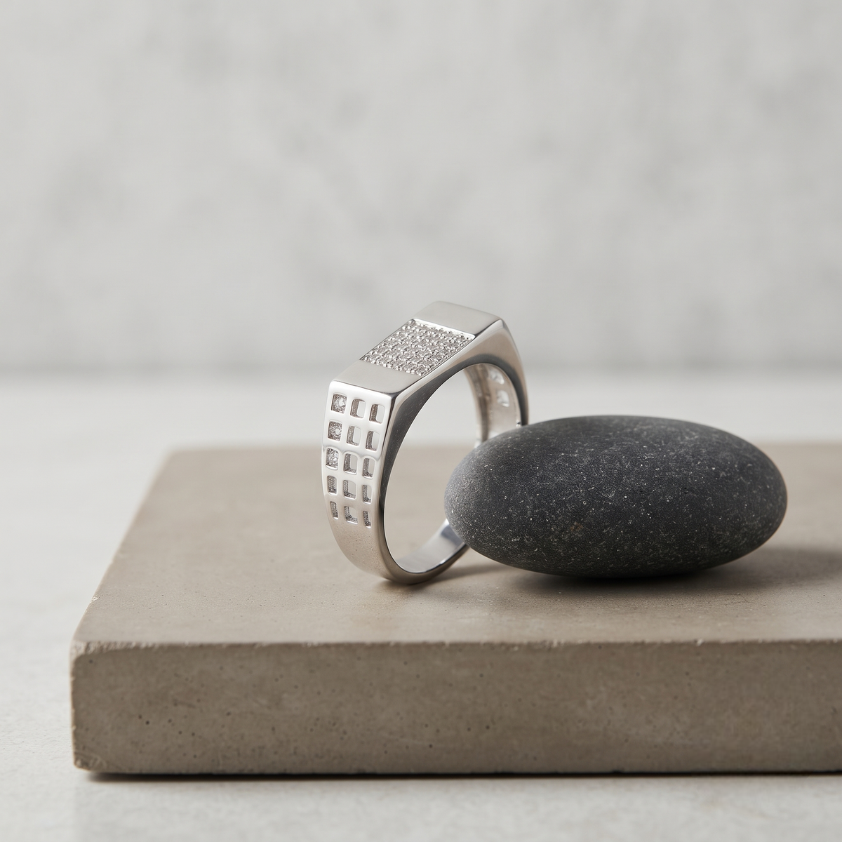 Silver ring with a rectangular stone-studded face and square lattice cutout band.