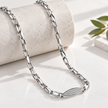 Silver paperclip chain with an oval stone-studded centrepiece.