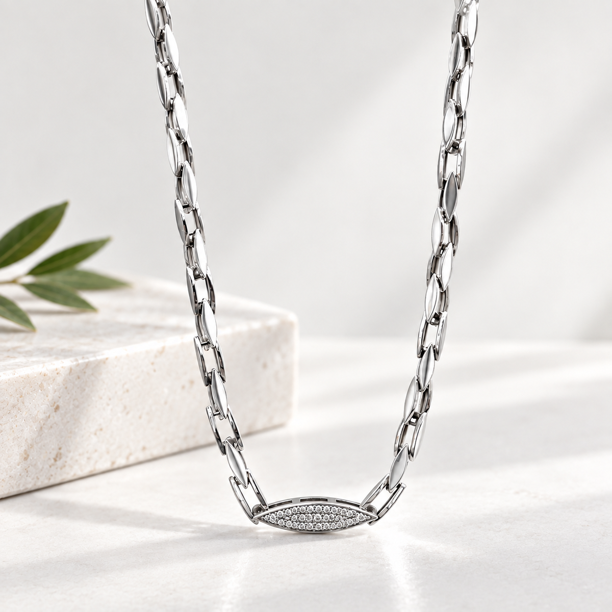 Silver paperclip chain with an oval stone-studded centrepiece.