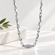 Silver paperclip chain with an oval stone-studded centrepiece.