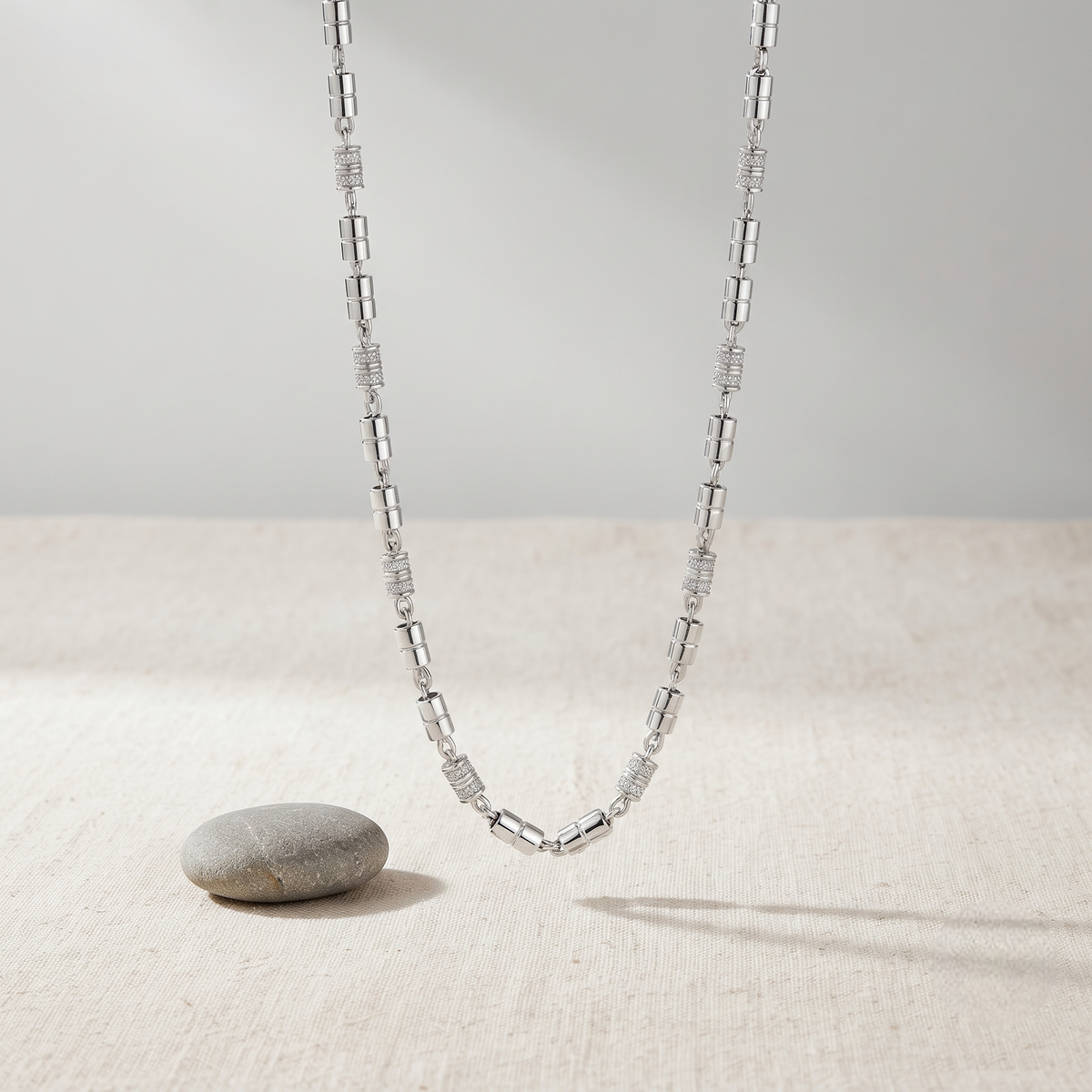 Silver chain with alternating polished cylindrical links and stone-studded barrel accents.