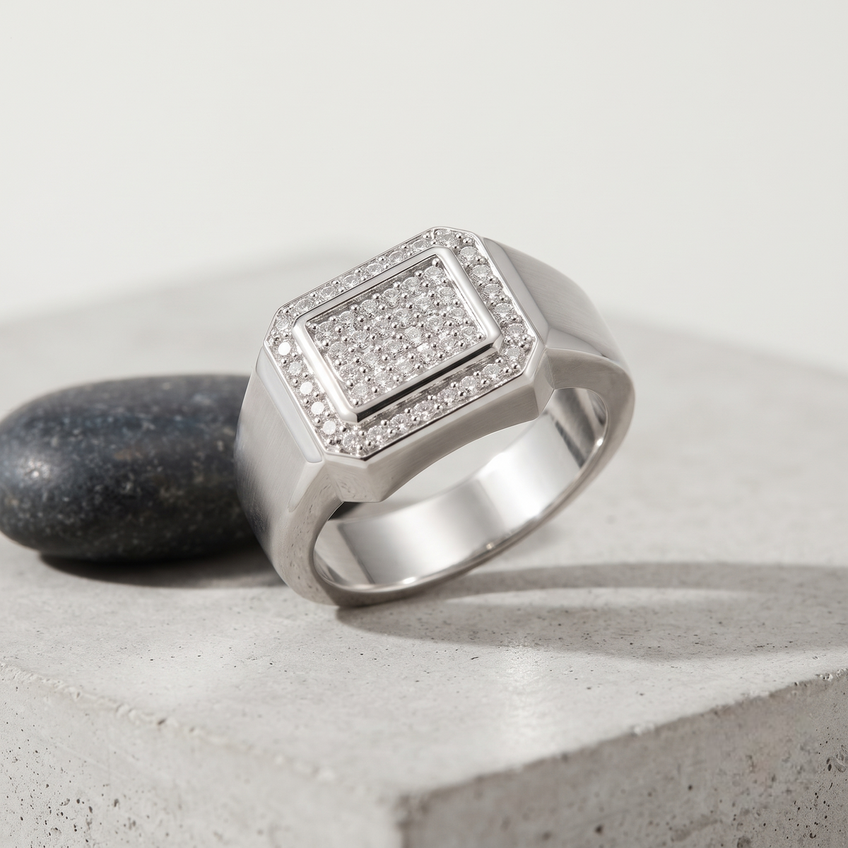 Silver ring with a square pavé-set centre, stone-studded halo and wide polished band.