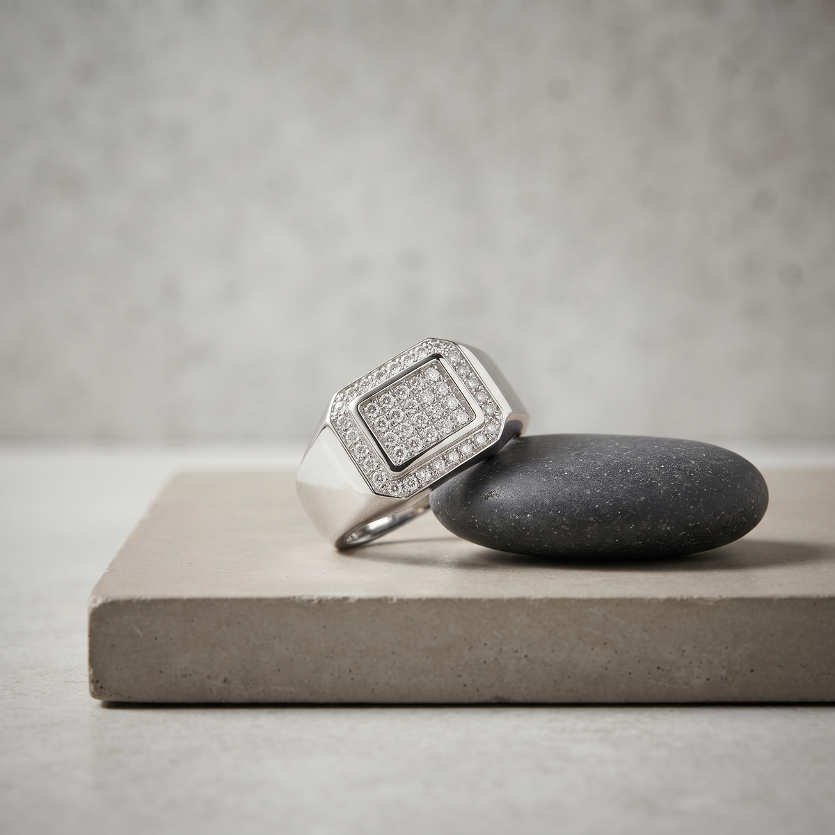 Silver ring with a square pavé-set centre, stone-studded halo and wide polished band.