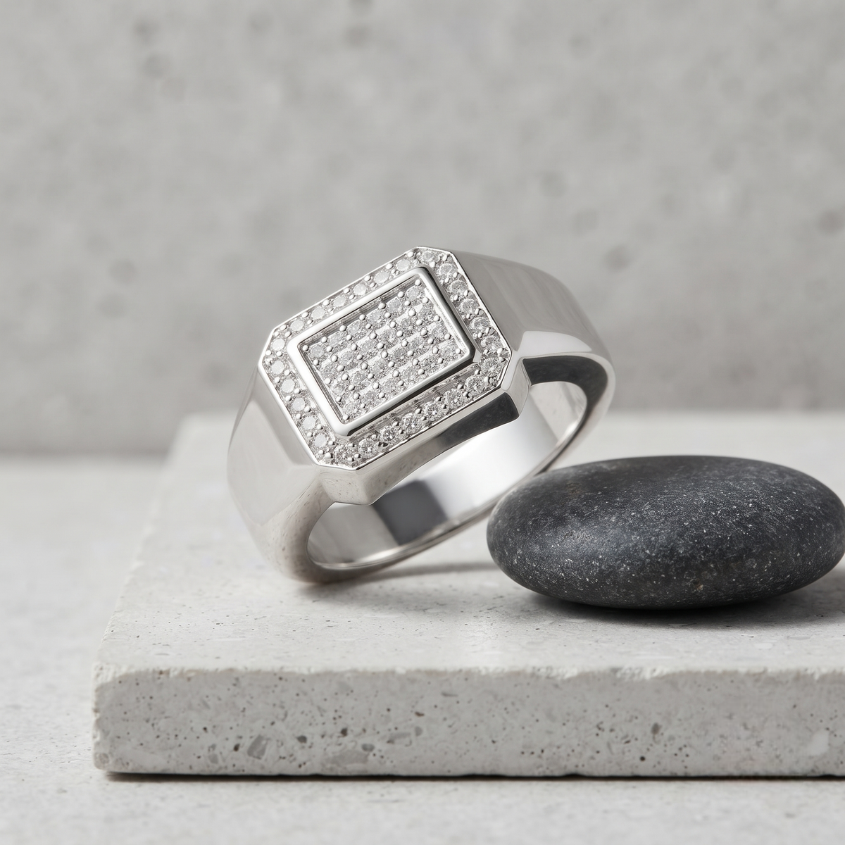 Silver ring with a square pavé-set centre, stone-studded halo and wide polished band.