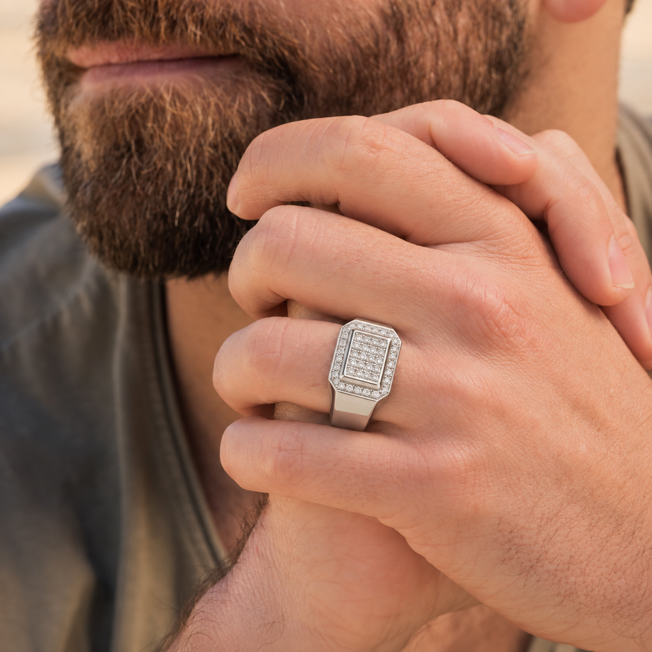 Silver ring with a square pavé-set centre, stone-studded halo and wide polished band.