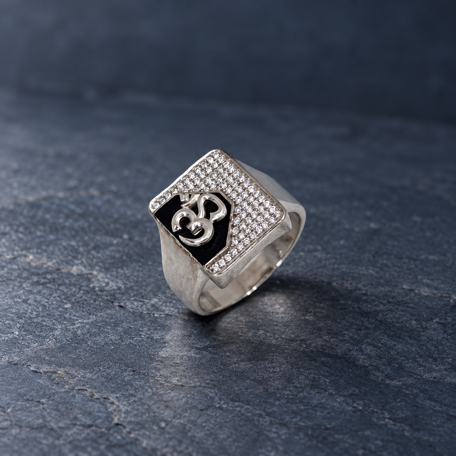 Silver ring with an Om symbol on a black centre and square stone-studded border.