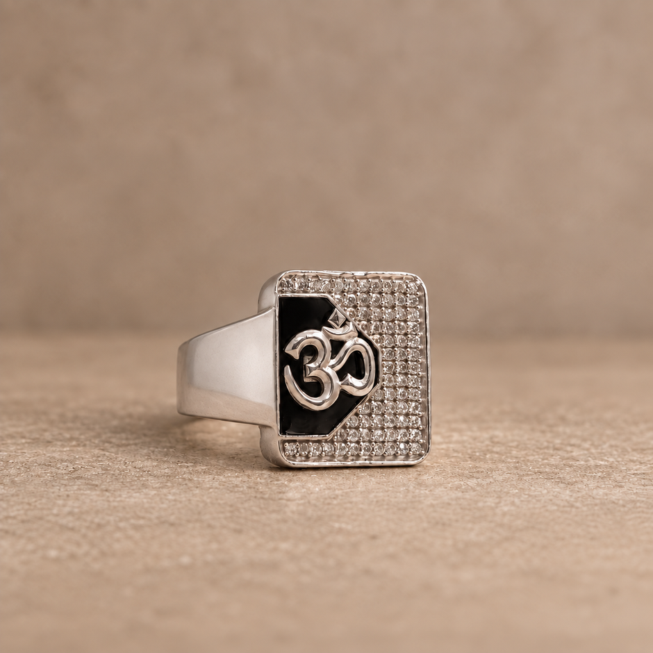 Silver ring with an Om symbol on a black centre and square stone-studded border.
