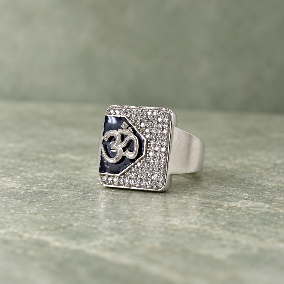 Silver ring with an Om symbol on a black centre and square stone-studded border.