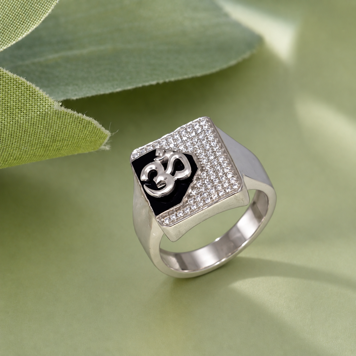 Silver ring with an Om symbol on a black centre and square stone-studded border.