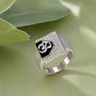 Silver ring with an Om symbol on a black centre and square stone-studded border.