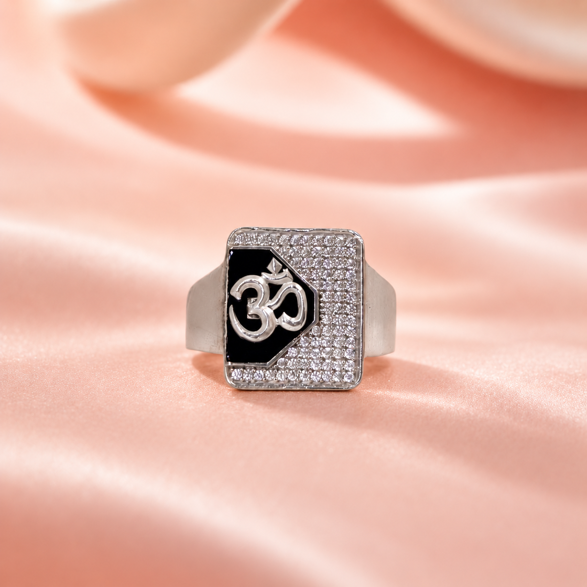 Silver ring with an Om symbol on a black centre and square stone-studded border.