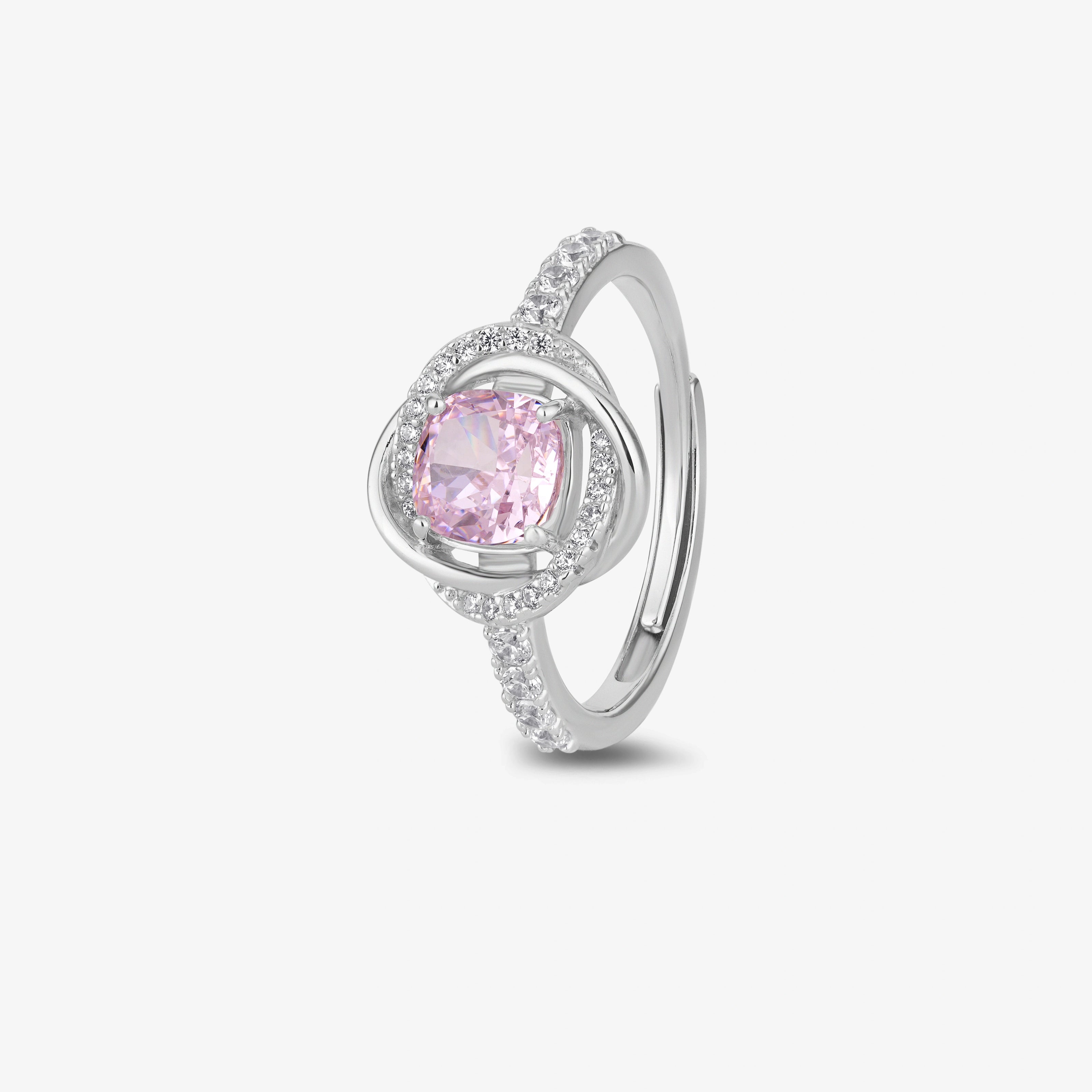 Pink cubic zirconia halo ring in 925 sterling silver displayed on a sandy beach with ocean waves and seashells, showcasing elegant women's jewelry in a coastal setting.