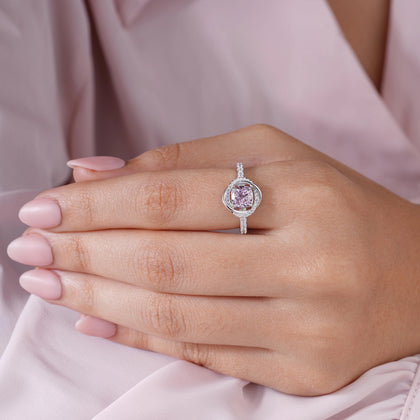 Pink cubic zirconia halo ring in 925 sterling silver displayed on a sandy beach with ocean waves and seashells, showcasing elegant women's jewelry in a coastal setting.