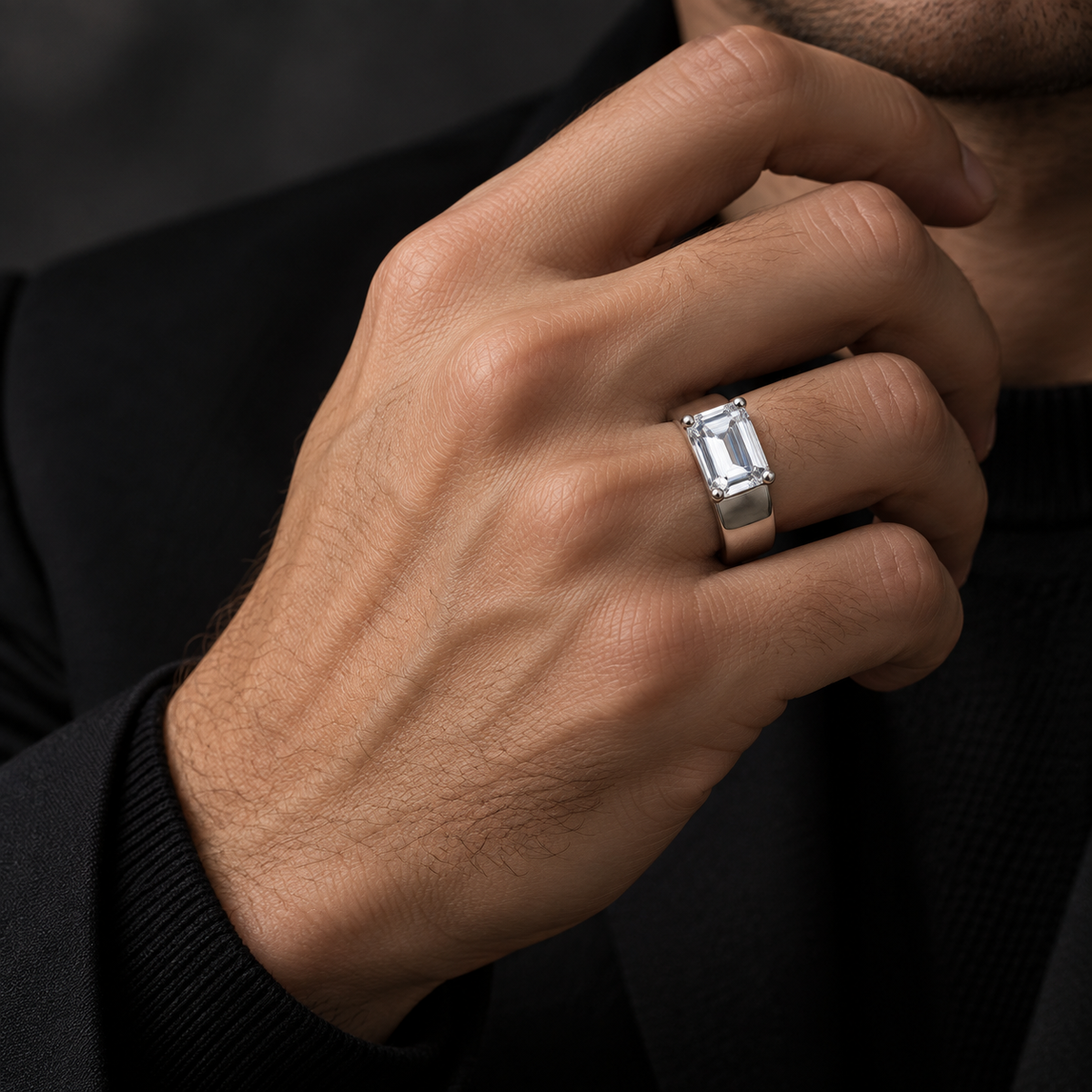 Silver ring with an emerald-cut clear solitaire stone and wide polished band.